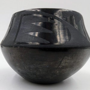 May include: Black pottery bowl with a geometric design. The bowl is made of black clay and has a smooth, glossy finish.