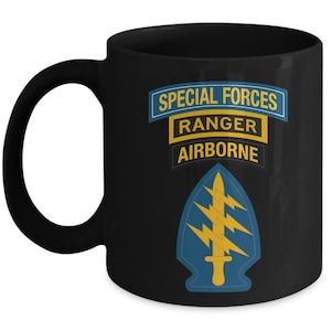May include: Black ceramic mug featuring the text "SPECIAL FORCES RANGER AIRBORNE" in blue and yellow. Below the text is a blue and yellow emblem with a sword and lightning bolts. The mug has a black handle.
