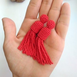 May include: A pair of red beaded tassel earrings. The tassels are made of small, red beads and are about 2 inches long.