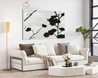 May include: A large rectangular canvas art piece with a black floral design against a white and gray background. The artwork hangs above a white sofa with throw pillows and a blanket. The room is well-lit with a floor lamp.