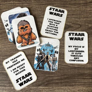 May include: A collection of Star Wars-themed cards featuring characters like Chewbacca and various quotes. The cards have a white background with gold trim and include phrases such as "My training has prepared me" and "My focus is my lightsaber."