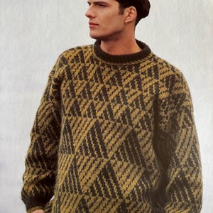 Può includere: Un maglione con motivo verde scuro e oro con scollo tondo. Il maglione presenta un design geometrico. Le maniche sono lunghe e la vestibilità sembra ampia. Il maglione è realizzato in un materiale a maglia spesso.