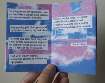 Puede incluir: Un libro pequeño, rosa y azul con texto impreso en las páginas. El texto dice: "Echando un vistazo a mi apartamento, puedo ver que el menú de género de hoy incluye, pero no está necesariamente limitado a: La creciente pila de libros sin abrir y sin terminar en mi silla de escritorio El pequeño búho de cristal azul que compré por unos pocos euros en una tienda de antigüedades en verano, que está posado en la mesa del televisor en mi sala de estar. Ese tarro de cerezas al marrasquino (probablemente caducadas) en la parte de atrás de mi refrigerador. Esto quiere decir que hoy, mi género podría ser Miedo, un objeto inanimado precioso y misterioso, y/o posiblemente basura literal. Qué casualidad. ¡Qué emocionante!"