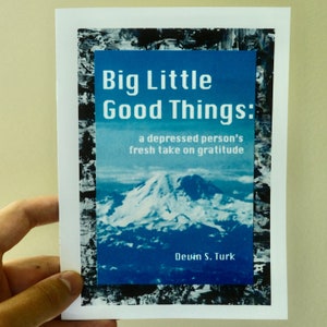 以下が含まれることがあります： 青と白の山が描かれた本の表紙。タイトルは「Big Little Good Things: a depressed person's fresh take on gratitude」。著者はデビン・S・タークです。