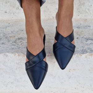 May include: Black leather pointed-toe mules with criss-cross straps.