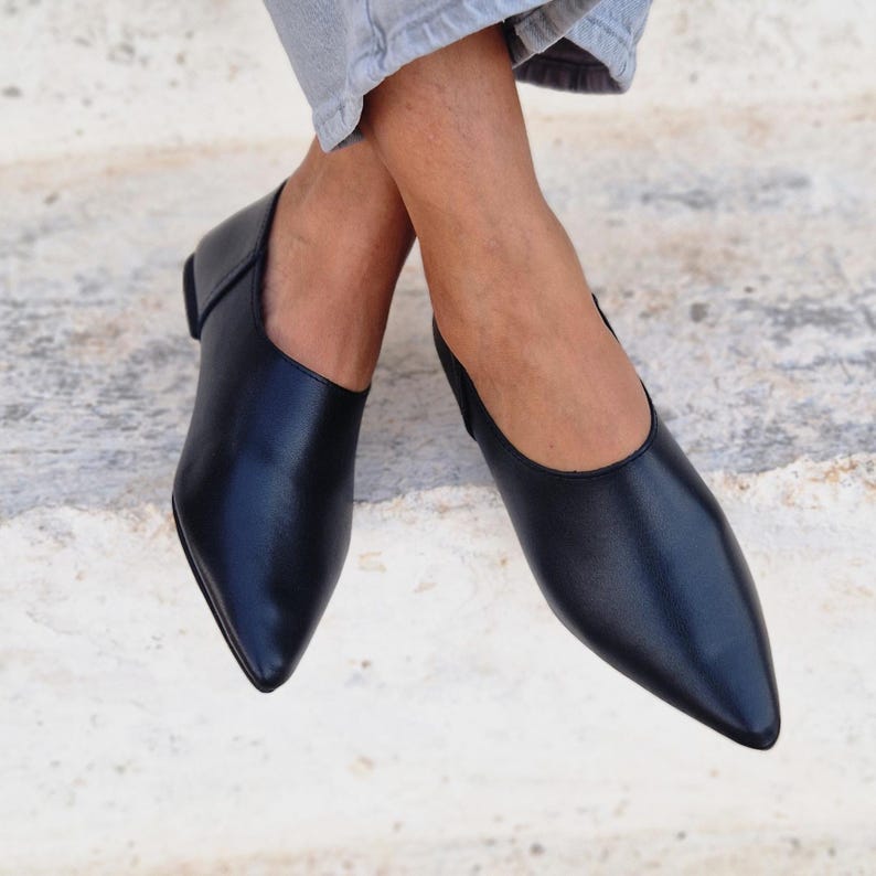 Pode incluir: Um par de sapatos baixos de bico fino em couro preto. Os sapatos t&ecirc;m um design simples e elegante e s&atilde;o perfeitos para uma variedade de ocasi&otilde;es.