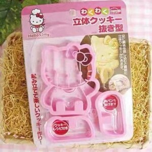 May include: Pink Hello Kitty cookie cutter set. The set includes a three-part cutter for creating 3D cookies. The packaging features Japanese text and an image of a finished cookie. The set is designed for making cookies and includes a recipe.