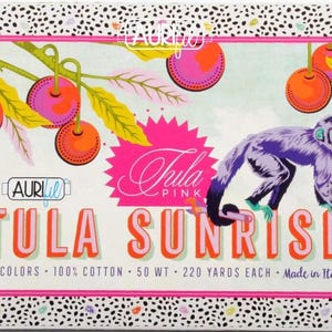 May include: A Tula Pink fabric collection called "Tula Sunrise" featuring a monkey, cherries, and a pink and white floral design. The label says "20 colors - 100% cotton - 50 wt - 220 yards each - Made in Italy."