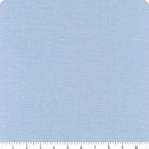 May include: A square of light blue fabric with a subtle woven texture. The fabric has a solid color and a slightly rough appearance, suggesting it might be cotton or a similar material. The color is a soft, pale blue, suitable for various sewing projects.