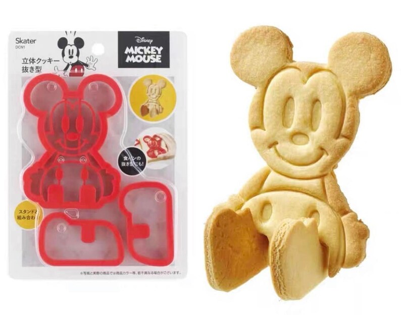 May include: A red plastic Mickey Mouse cookie cutter set next to a baked Mickey Mouse cookie. The packaging includes the Disney Mickey Mouse logo and Japanese text. The cookie cutter is designed to create a 3D cookie.