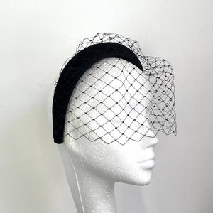 May include: Black velvet headband with a black tulle veil attached. The veil is a fine mesh with a diamond pattern.