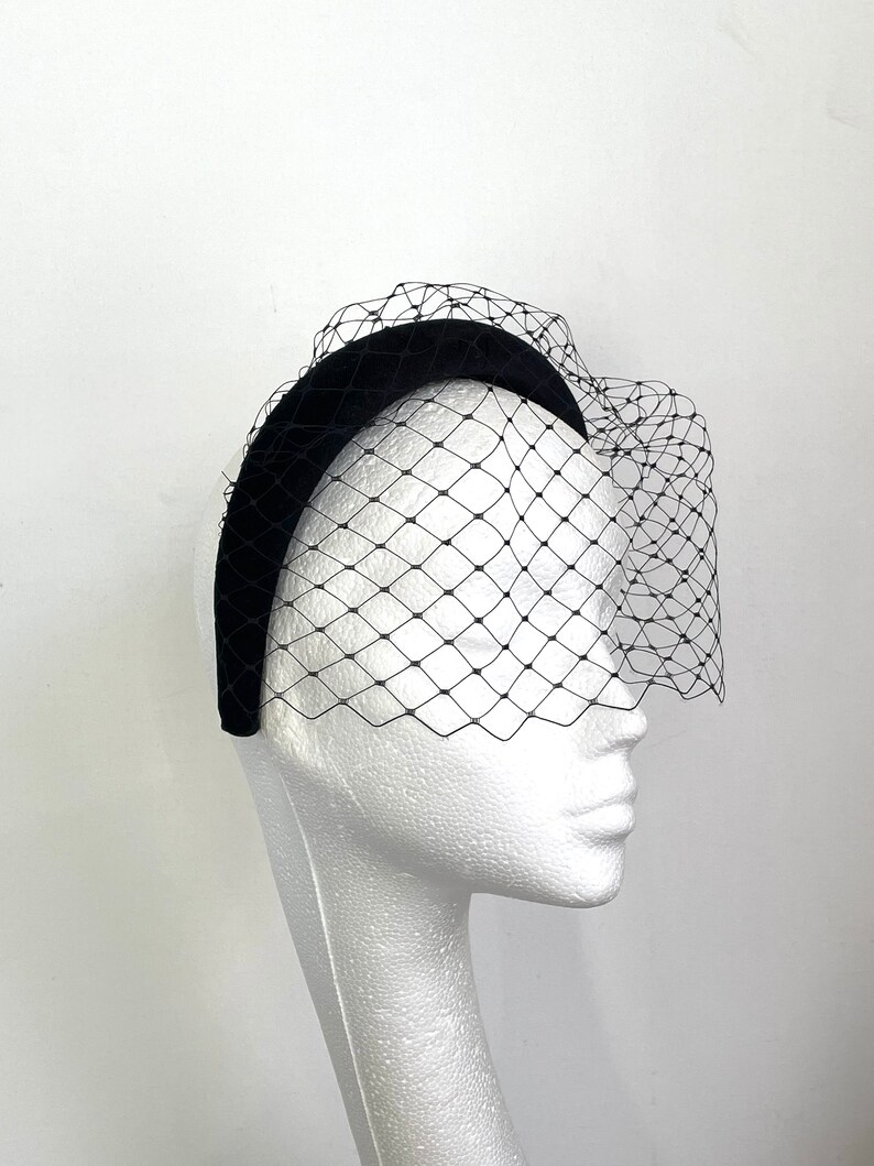 May include: Black velvet headband with a black tulle veil attached. The veil is a fine mesh with a diamond pattern.