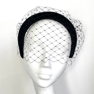 May include: A black velvet headband with a black tulle veil. The headband is wide and has a slight curve. The veil is delicate and has a diamond pattern.