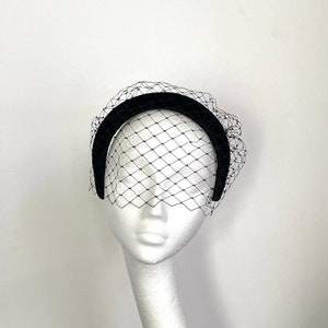 May include: Black velvet headband with a black birdcage veil. The headband is curved and the veil is made of a fine mesh.