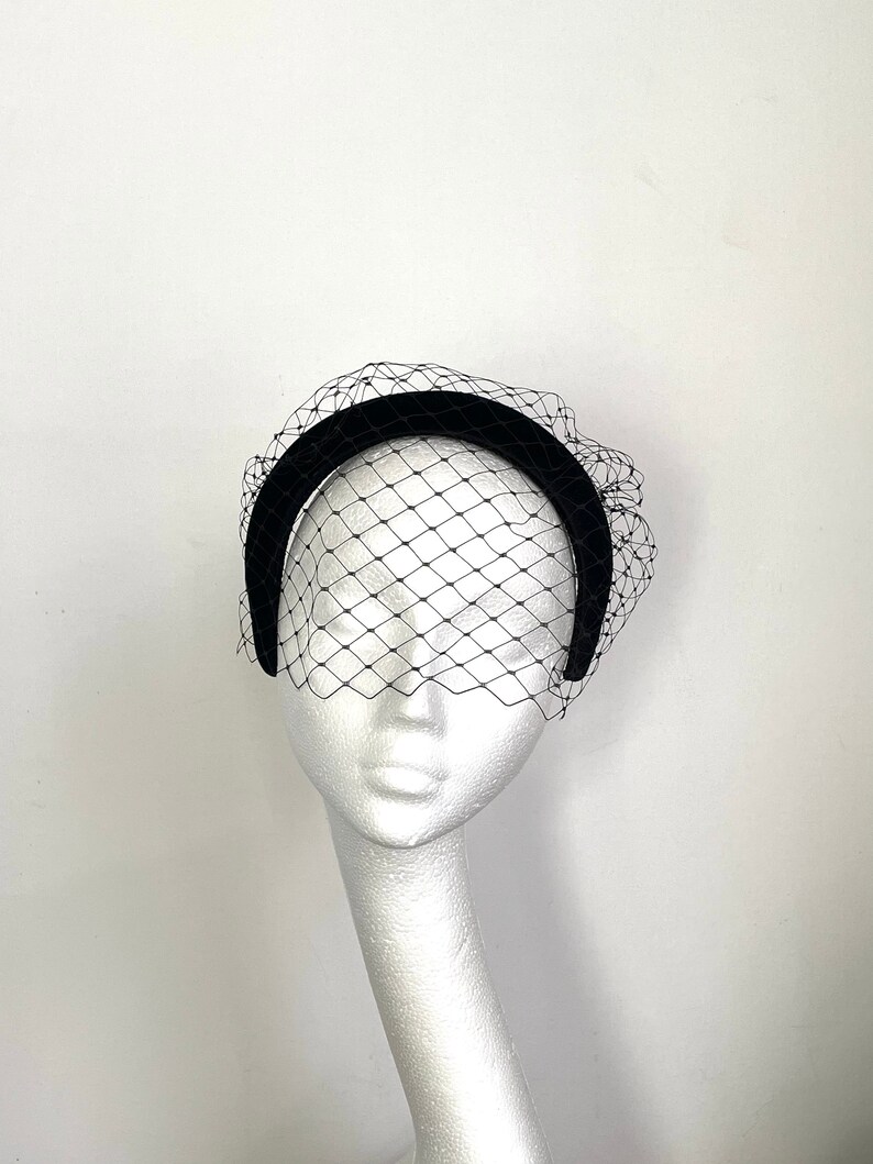 May include: Black velvet headband with a black birdcage veil. The headband is curved and the veil is made of a fine mesh.