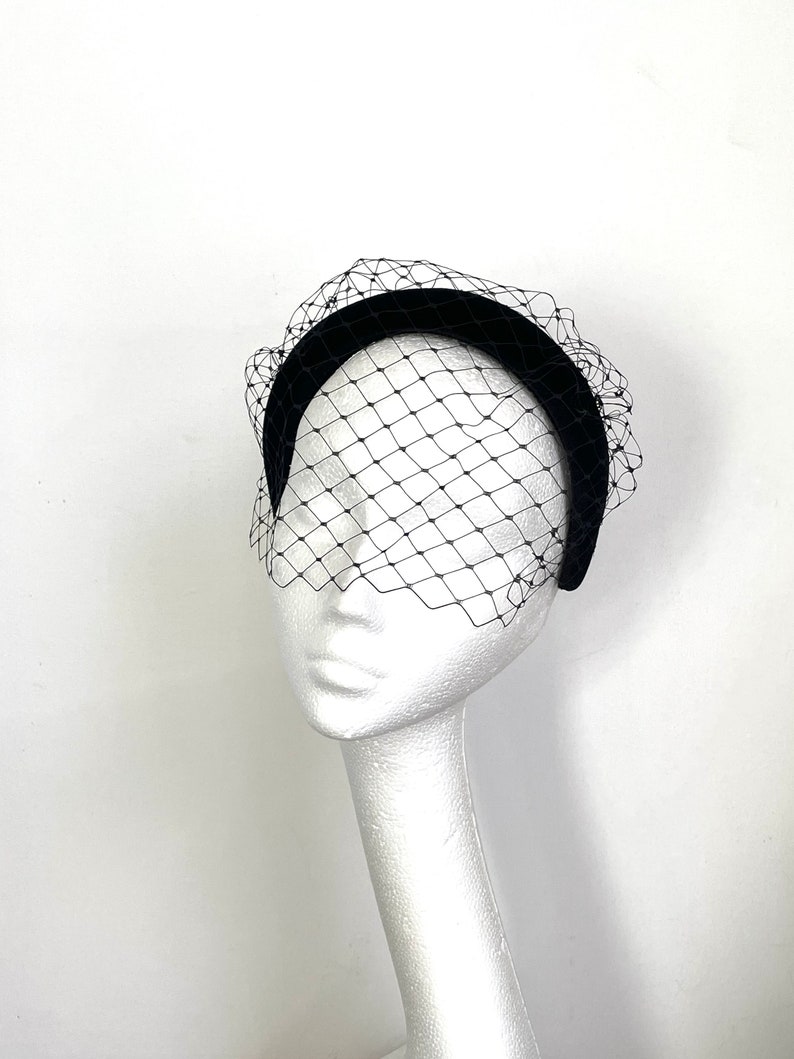 May include: A black velvet headband with a black tulle veil. The veil has a diamond pattern.