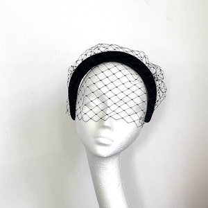 May include: Black velvet headband with a black tulle veil. The headband is curved and the veil is gathered at the top.