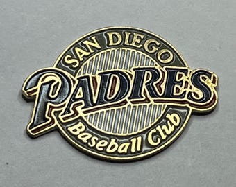 May include: A circular San Diego Padres baseball club pin. The pin features the team's logo with the words "San Diego Padres Baseball Club" in gold, black, and navy blue. The pin has a gold border.