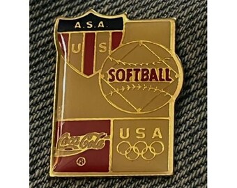 May include: Gold-colored pin with a red, white, and blue shield with the letters "A.S.A." and "U.S.A."  The shield is above a gold softball with the word "SOFTBALL" in red letters.  The bottom of the pin has a red Coca-Cola logo and the words "USA" in gold letters with five gold Olympic rings.