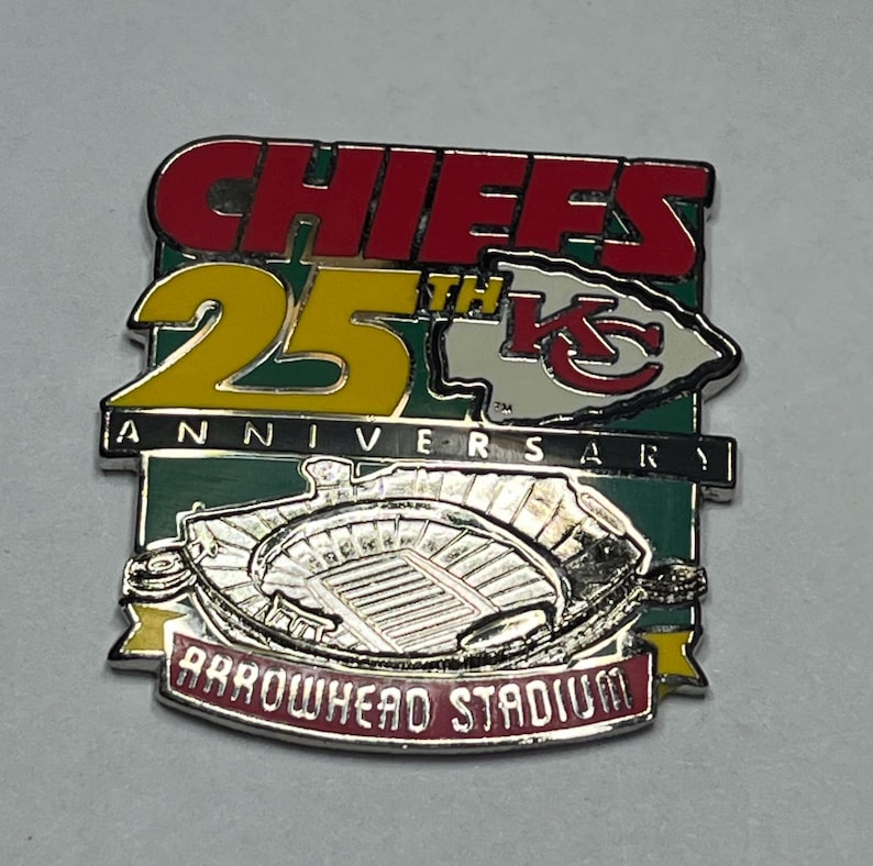 May include: A Chiefs 25th Anniversary pin featuring the team's logo, the words "CHIEFS" in red, and "25th ANNIVERSARY" in yellow. The pin also includes an image of Arrowhead Stadium.