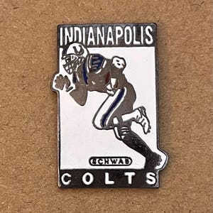 Puede incluir: Pin rectangular de los Colts de Indianápolis con un gráfico de un jugador de fútbol americano. El pin presenta las palabras "INDIANAPOLIS" y "COLTS". El jugador está en una pose de carrera, con detalles en azul y blanco.