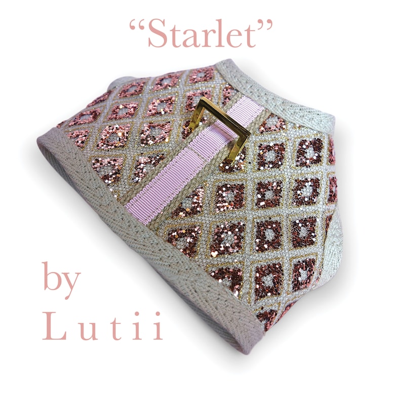 K&ouml;nnte beinhalten: Ein beigefarbenes Hundegeschirr mit einem geometrischen Muster in Rosa und Gold und einer goldenen Schnalle. Das Geschirr ist mit "Starlet" von "Lutii" gekennzeichnet.