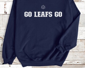 May include: Navy blue sweatshirt with the text "GO LEAFS GO" in white block letters. A small white maple leaf is above the text. The sweatshirt is made of a soft material.