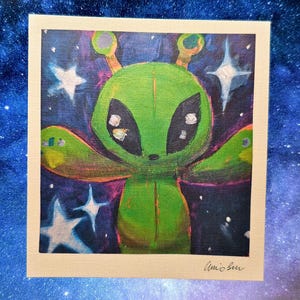 May include: A green alien with large black eyes and outstretched arms is depicted in a painting. The alien is set against a dark blue and purple background with white stars. The artwork is signed in the bottom right corner.