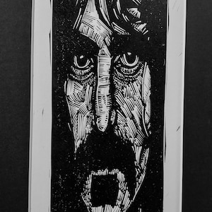 May include: Black and white woodcut print of Frank Zappa's face. The print is signed "Frank Zappa" and "Sean Eaby".