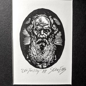 May include: Black and white linocut print of Leo Tolstoy in an oval frame. The portrait features a detailed depiction of Tolstoy's face, beard, and hair. The print is signed "Sean Fary" and includes the text "Leo Tolstoy" at the bottom.