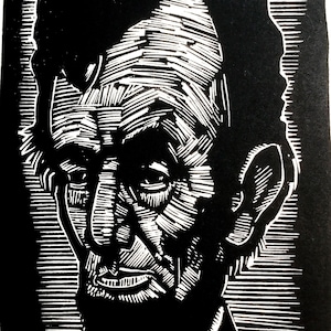 May include: Black and white woodcut print of a man's face. The man has a serious expression and is looking to the left. The print is detailed and shows the lines of the man's face.