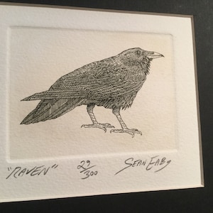 May include: A black and white line drawing of a raven, signed by the artist "Sean Eaby" and numbered 22/300. The image is titled "RAVEN".