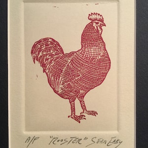 May include: A red rooster illustration in a white matted frame with a black frame. The image is signed "A/P "Rooster" Sean Eaby".