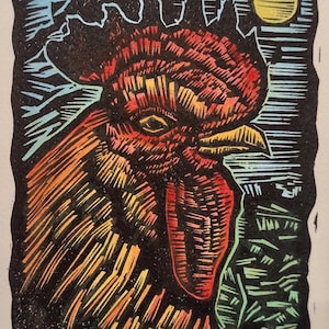 May include: A colorful woodcut print of a rooster with a red comb and wattle, and yellow, orange, and black feathers. The background features a yellow moon, blue sky, and green grass. The text "Proud Rooster" is at the bottom.