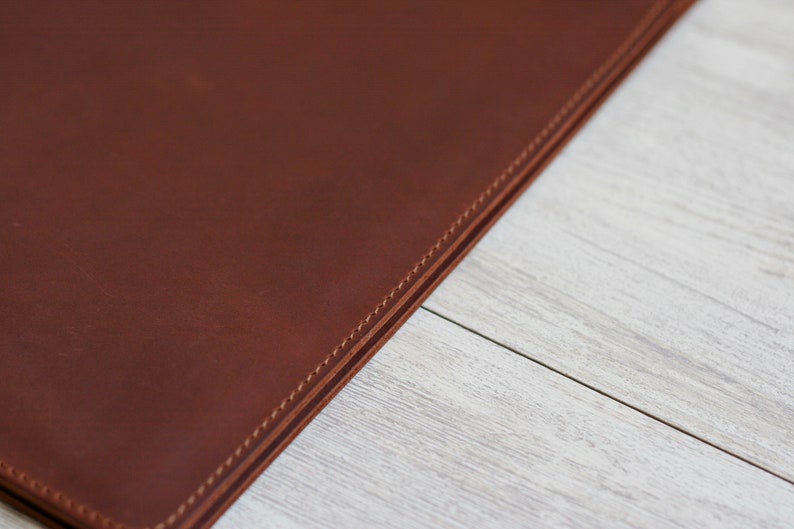 May include: Close-up of a brown leather surface with double stitching along the edge.