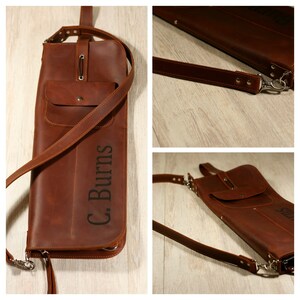 K&ouml;nnte beinhalten: Eine braune Ledertasche mit Rei&szlig;verschluss und einer kleinen Tasche auf der Vorderseite. Die Tasche hat einen langen verstellbaren Riemen und ist mit dem Namen "C. Burns" personalisiert.
