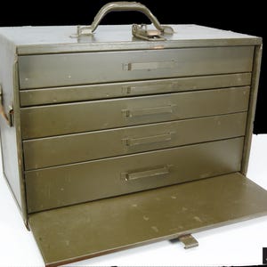 May include: Olive green metal toolbox with a handle and four drawers. The bottom drawer is open, revealing the interior. The toolbox has a latch closure and is set against a black background.