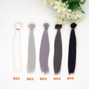 May include: Five bundles of doll hair in various colors: white, gray, lavender, dark gray, and black. Each bundle is tied with a different colored band. The text "B01", "B02", "B03", "B04", and "B05" is printed below each bundle.