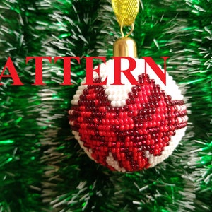May include: Red and white beaded Christmas ornament with a heart-shaped design. The ornament is hanging from a green Christmas tree.
