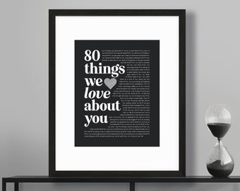 Könnte beinhalten: Schwarz-Weiß-Druck mit dem Text "80 Dinge, die wir an dir lieben" in einer eleganten Schriftart. Der Druck enthält eine Liste von Gründen, jemanden zu lieben, mit einem Herz-Grafik. Der Rahmen ist schwarz.