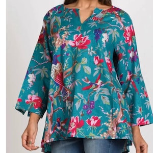 May include: A teal tunic featuring a vibrant botanical print with red flowers, green leaves, and colorful birds perched on branches. The top has a notched V-neckline, three-quarter length sleeves, and a slightly longer hemline in the back.