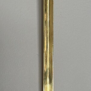 May include: A copper ladle with a brass handle. The ladle's bowl is a warm copper color, while the handle is a shiny brass. The handle is long and slender, with a curved end for hanging. A kitchen utensil.