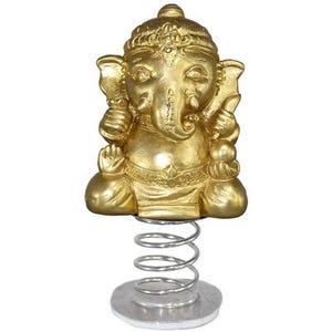 May include: A golden statue of the Hindu deity Ganesha, seated with hands raised, atop a silver spring and base. The statue has detailed features and is a decorative item.