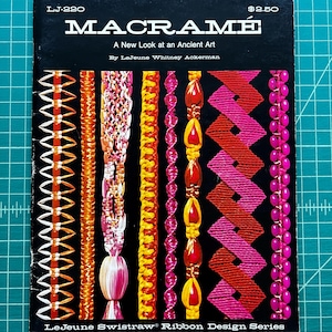 May include: A black instructional book titled MACRAMÉ: A New Look at an Ancient Art by LeJeune Whitney Ackerman, featuring eight vertical columns of colorful knotted ribbon designs and beads on the cover, with the text LJ-220 and $2.50.