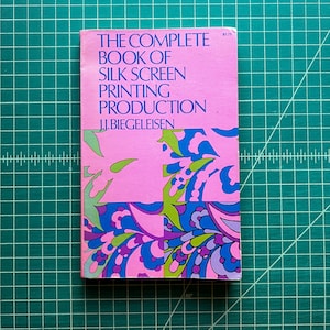 May include: A paperback book titled The Complete Book of Silk Screen Printing Production by J.I. Biegeleisen. The cover features a vibrant pink background with a colorful abstract pattern of blue, purple, and green shapes at the bottom.
