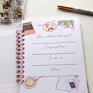 May include: A spiral-bound notebook with rose gold accents, open to a page with the text "This notebook belongs to:" and lines for Congregation, Email, and Phone. The page is decorated with illustrations of a laptop, coffee, and flowers.
