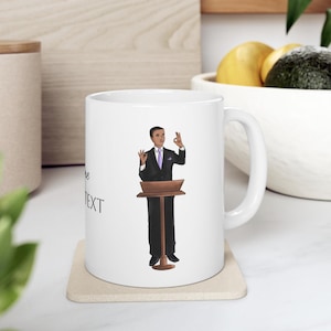 May include: White ceramic mug with a black and white illustration of a person giving a speech at a podium. The text "some text" is printed on the mug.