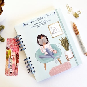 Puede incluir: Un cuaderno espiral azul y blanco con una ilustración colorida de una mujer leyendo un libro en una silla. El cuaderno tiene el texto "Mis notas de Estudio Personal" y un versículo bíblico en español.