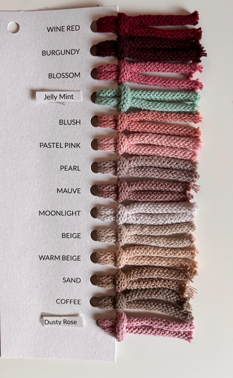 K&ouml;nnte beinhalten: Eine Farbmusterkarte mit vierzehn geflochtenen Kordelmustern in verschiedenen Farbt&ouml;nen, darunter Wine Red, Burgundy, Blossom, Jelly Mint, Blush, Pastel Pink, Pearl, Mauve, Moonlight, Beige, Warm Beige, Sand, Coffee und Dusty Rose mit Beschriftung.