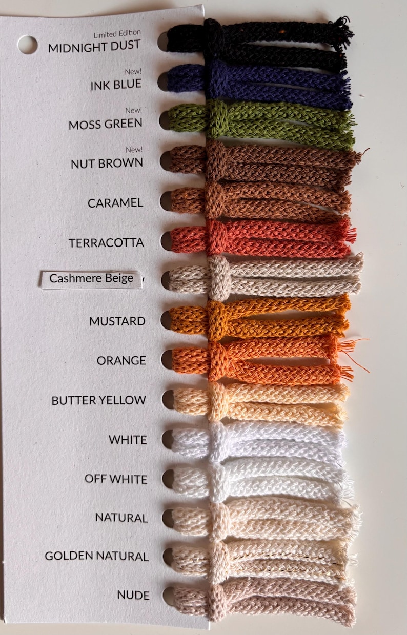K&ouml;nnte beinhalten: Eine Farbmusterkarte mit vierzehn geflochtenen Kordelmustern in verschiedenen Farbt&ouml;nen, darunter Midnight Dust, Ink Blue, Moss Green, Nut Brown, Caramel, Terracotta, Cashmere Beige, Mustard, Orange, Butter Yellow, White, Off White, Natural, Golden Natural und Nude.